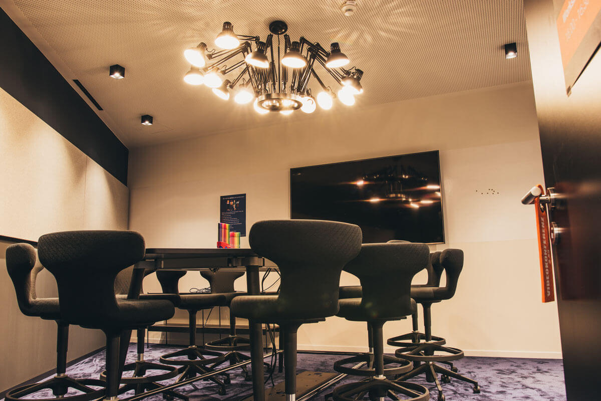 sovendus_meetingraum-2 Ein Meetingsraum im Sovendusbüro, ausgestattet mit Whiteboards, Bildschirm und hochwertigen Möbel, sowie einer ausgefallenen Deckenlampe.