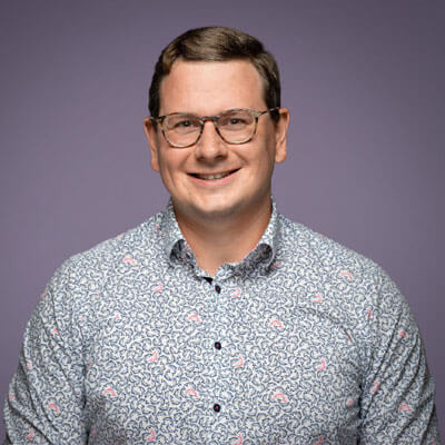 Lächelnder Mann mit gemustertem Hemd und Brille